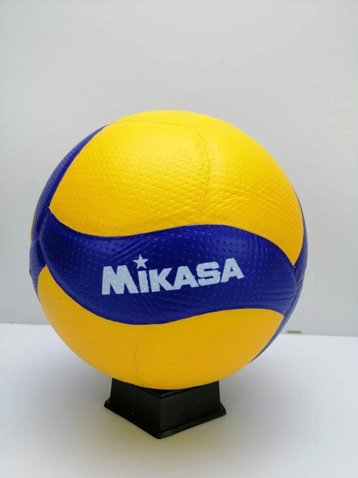 A Mikasa volleyball with yellow and blue panels, displayed on a black stand against a plain white background.
