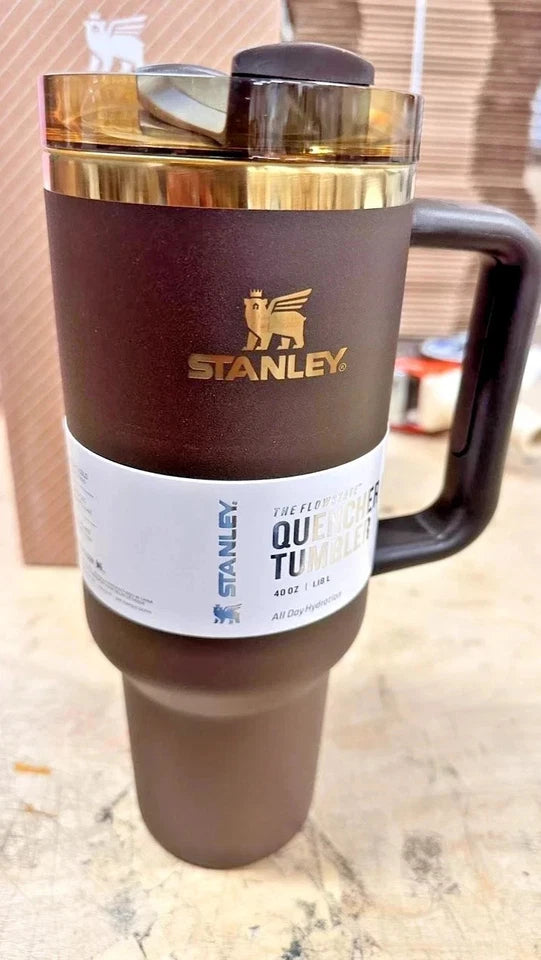 A brown insulated travel mug with a black lid and handle, featuring a white label with a camel logo and the brand name 'Camel'.