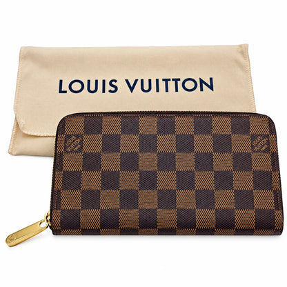 Louis Vuitton zip-around wallet in the Damier Ebene check pattern, shown with its beige dust bag on a white background.