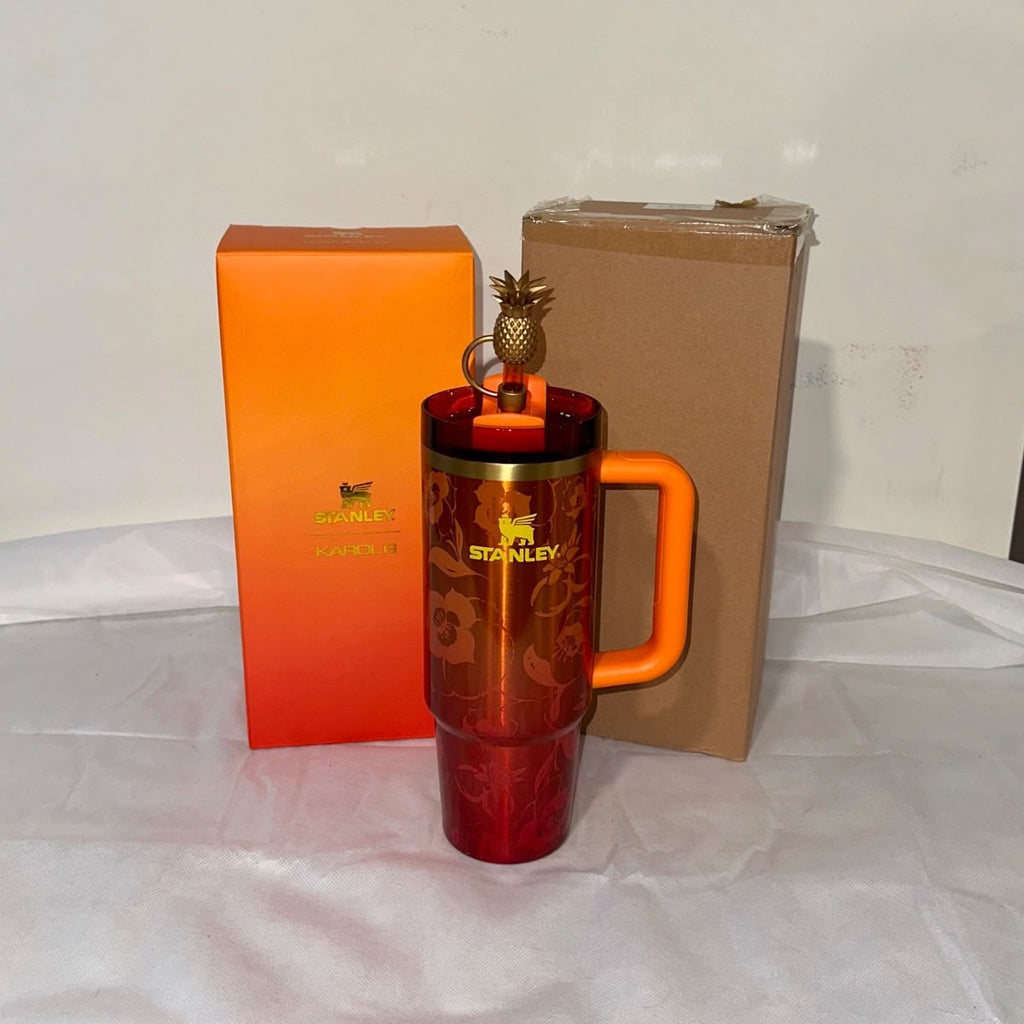 Red Stanley mug with orange handle and packaging on a white surface