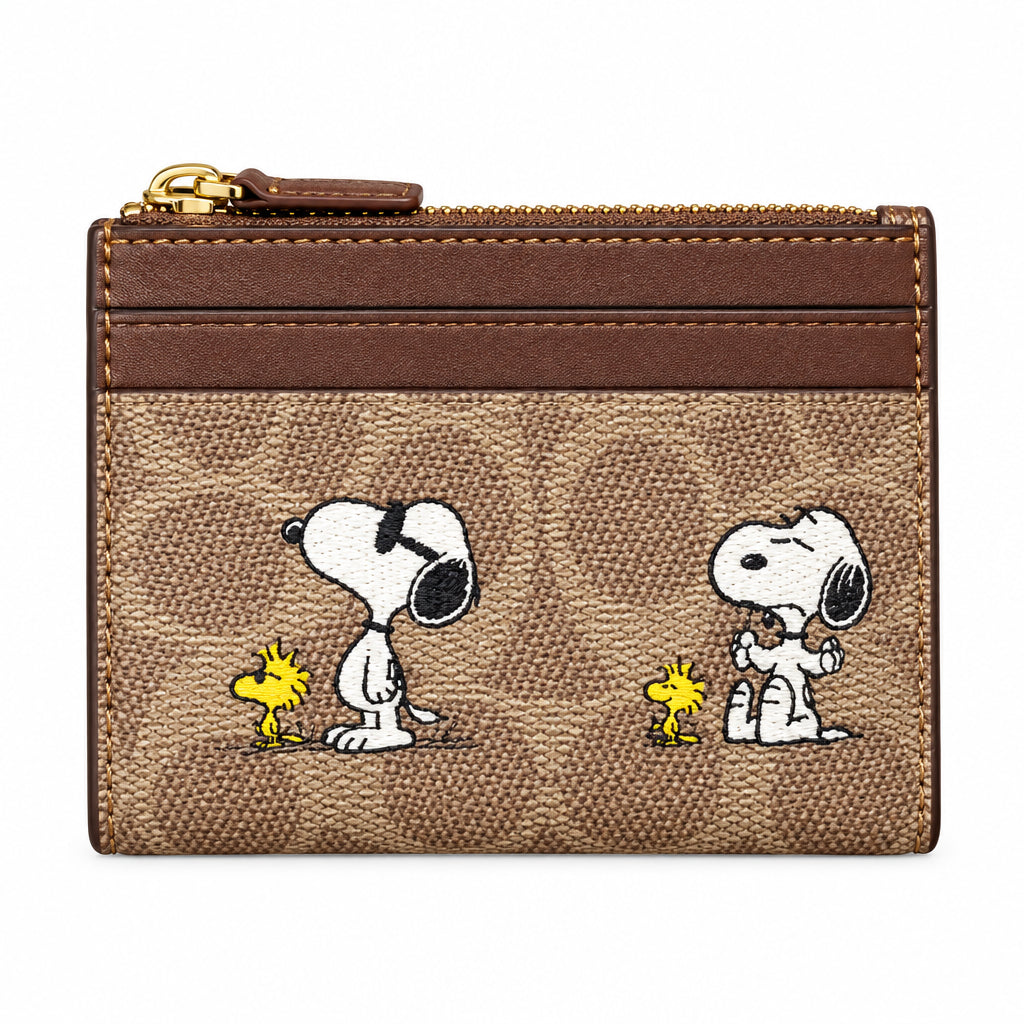 A hand holding a brown Snoopy and Woodstock card holder wallet with the classic Colette pattern, set against a store background.