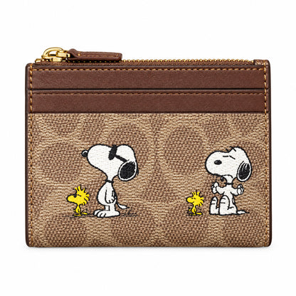 A hand holding a brown Snoopy and Woodstock card holder wallet with the classic Colette pattern, set against a store background.