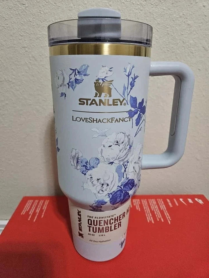 Stanley tumbler with floral design on a red surface