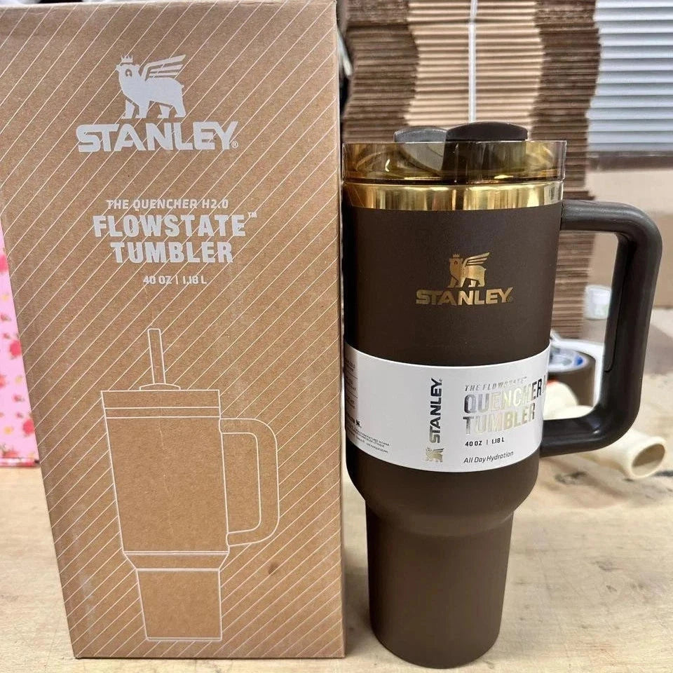 A dark brown Stanley Quencher 40 oz tumblers shown next to its original brown cardboard packaging box on a wooden surface.