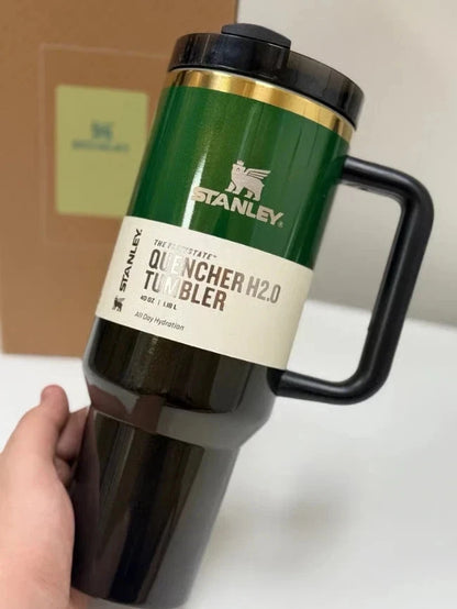 Green Stanley Quencher H2.0 tumbler held by a hand on a white surface.