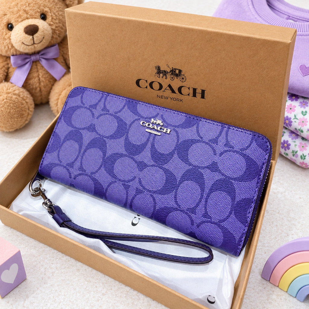 A purple Coach wallet with the signature C logo pattern, resting inside its brown cardboard box on white tissue paper.