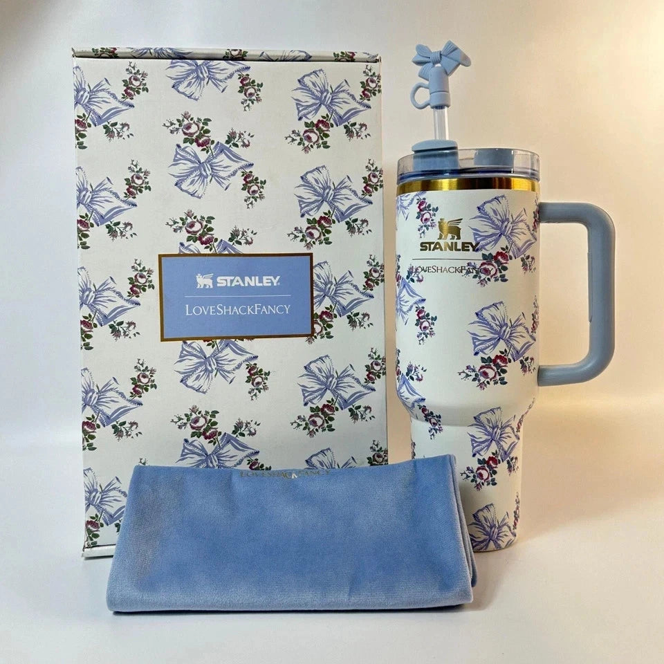 Stanley mug with floral design and matching blue towel in front of a floral-patterned box